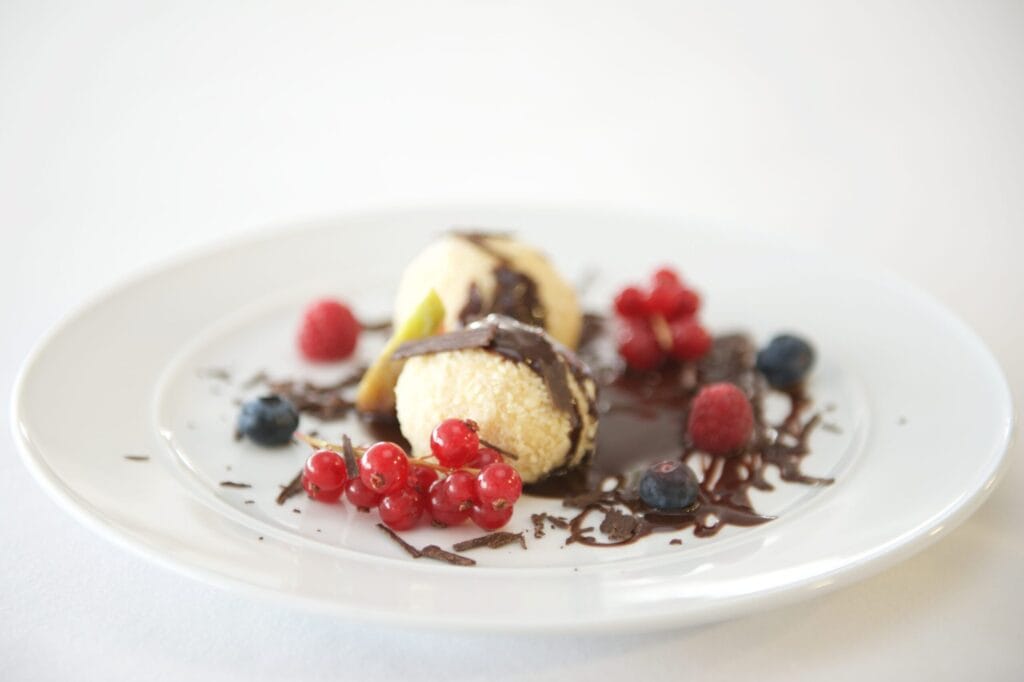 Sumptuous dessert with chocolate drizzle and mixed berries on a white plate.