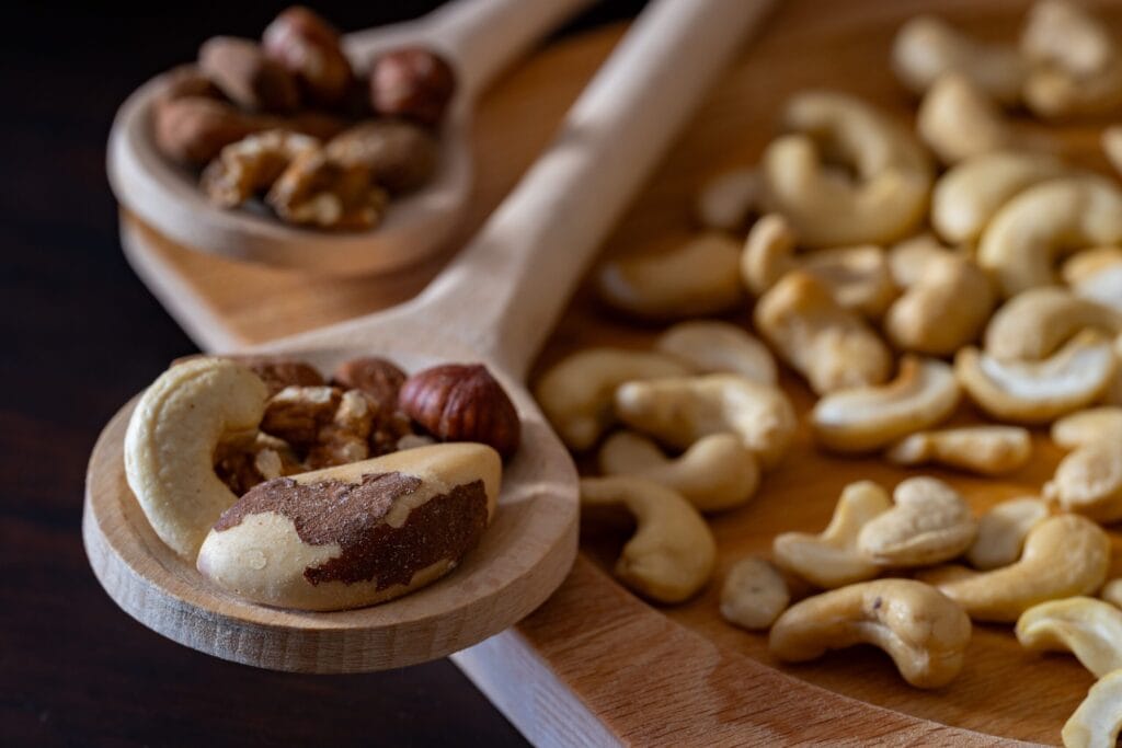 Close-up of mixed nuts including almonds, cashews, and walnuts on wooden spoons, ideal for healthy snacking.