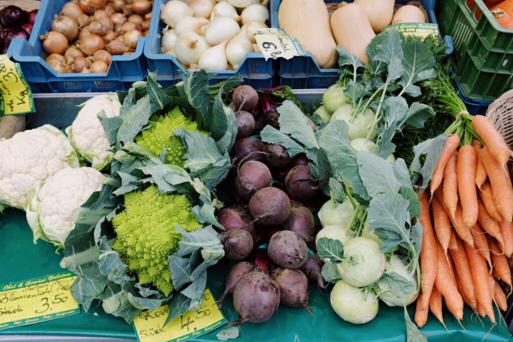 Vibrant collection of fresh vegetables including carrots, kohlrabi, and beets at a farmers' market.
