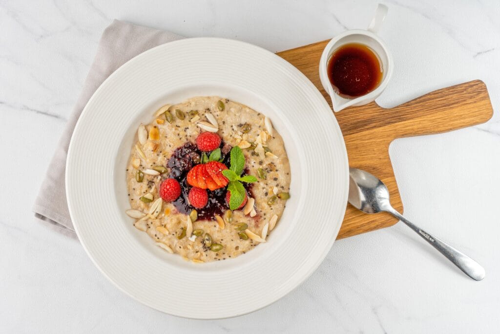 Delicious oatmeal bowl topped with fresh berries, almonds, pumpkin seeds, and mint.