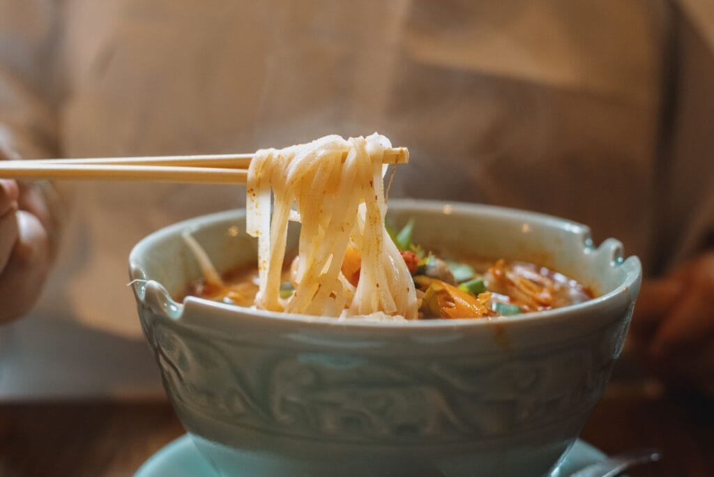 Close-up of traditional Japanese noodle soup being enjoyed with chopsticks in a ceramic bowl.