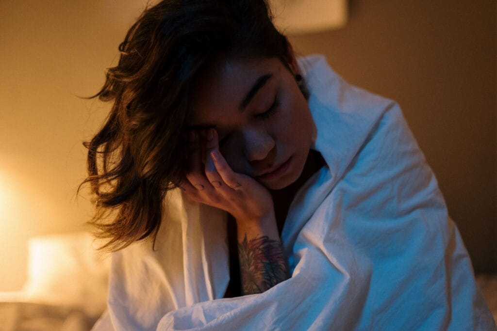 Woman in a cozy bedroom, wrapped in linen, enjoying a peaceful evening at home.