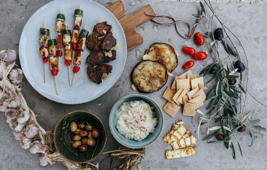A Mediterranean appetizer spread featuring skewers, dips, and assorted veggies. Perfect for gatherings.