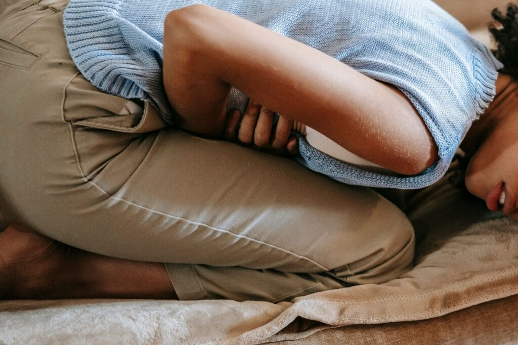 Side view of crop anonymous African American female in agony having acute stomach ache