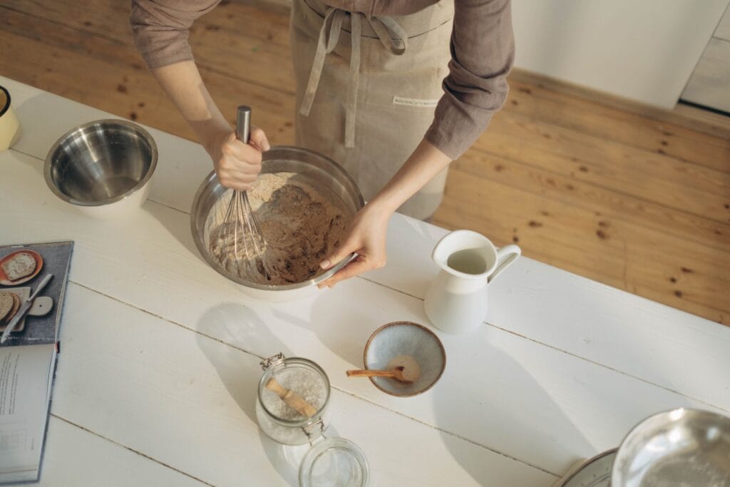 A baker mixes ingredients in a bowl on a kitchen counter, captured from above for an artistic view.